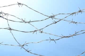 Metal barbed wire on light blue background