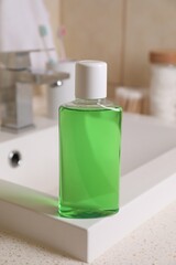 Fresh mouthwash in bottle on sink in bathroom, closeup
