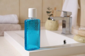 Fresh mouthwash in bottle on sink in bathroom, closeup