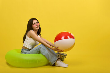Sporty popular model posing sitting in green inflatable swimming circle, holding multi-colored...