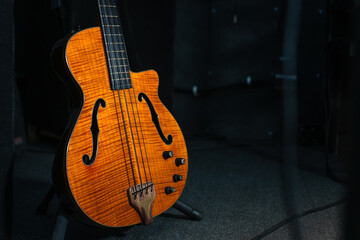Close-up of a beautiful electronic guitar stands on the floor in the studio, illuminated by light on the stage, copy space