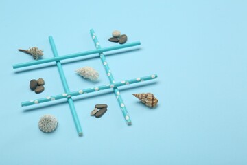 Tic tac toe game made with sea treasures on light blue background