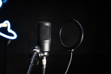 Close-up of a professional condenser studio microphone on a black background in a music studio.