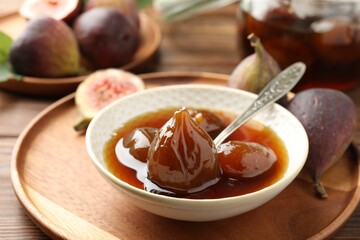 Bowl of tasty sweet fig jam on wooden table, closeup