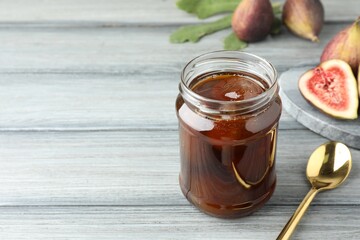 Jar of tasty sweet jam and fresh figs on grey table, space for text