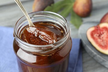 Jar of tasty sweet fig jam on table, closeup