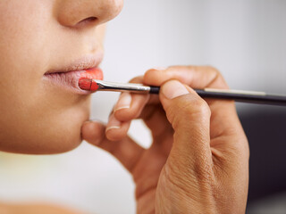 Closeup, woman and makeup brush on lips for beauty with hands, application of cosmetics product and...