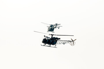 Two combat helicopter are flying against isolated white background