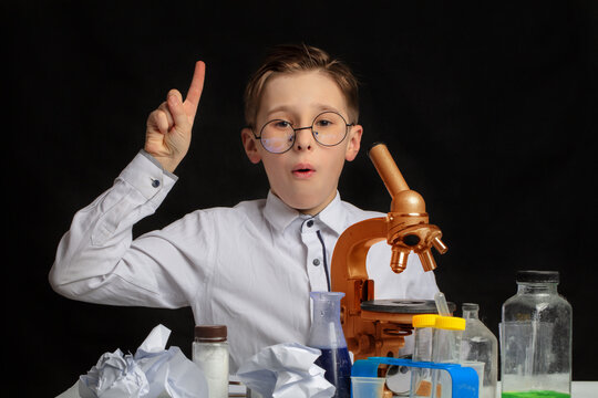An interesting discovery was made by a little scientist wearing glasses who was studying through a microscope. A cute boy chemist suddenly came up with an amazing idea in the laboratory.
