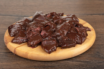 Raw peeled and chopped beef liver on a cutting board.
