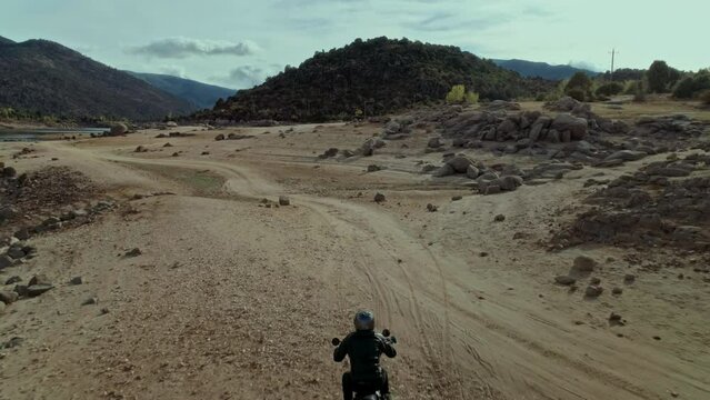 Camera follows rider on custom off road motorcycle on valley landscape. Motorcycle summer adventure. Motorbike enthusiast passion for extreme sport. Commercial advertising concept. 