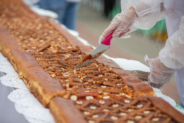 A chef's knife cuts yeast pies on an industrial tape.