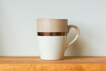A cup on a wooden shelf against a wall background