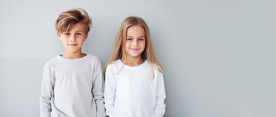 Brother and sister in light clothes, children standing next to each other and smiling, empty space for text, national siblings day, banner. Portrait of cute children on a light background - Powered by Adobe