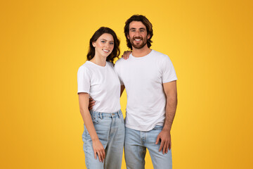 Fototapeta premium Smiling young couple standing together wearing white t-shirts and blue jeans