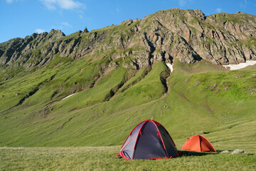 landscape with touristic tents in green big mountains and blue sky, nature background. trip, journey, hiking, adventure concept. summer season in Caucasus mountains, Karachay-Cherkess Republic. Arkhyz