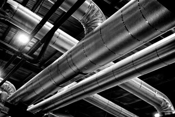 Black and white photograph of shiny pipes at an industrial oil refinery