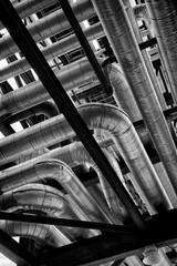 Black and white photograph of shiny pipes at an industrial oil refinery