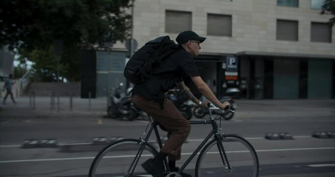 Side shot of stylish commuter ride minimalistic bicycle on the bike lane through business district in Barcelona. Student or IT specialist on his way to work. Reaching the destination. 