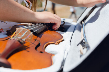 closeup of young unrecognizable busker woman on street keeping violin in case