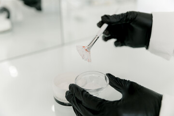 Cosmetologist is preparing a white facial mask using cosmetology powder and brush. 