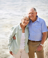 Senior, couple and happy portrait at beach for retirement vacation or anniversary to relax with love, care and commitment with support. Elderly man, woman and together by ocean for peace on holiday.