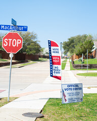 Street corner Stop and yard sign, vote banner flag show Official Vote Center in English, Spanish,...