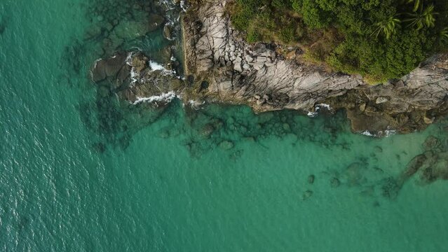Aerial top view 4k footage by drone of ocean blue waves break on high cliff of a rocky mountain.Dream trip to green island. Outdoor adventure travel to beautiful phuket thiland beach.