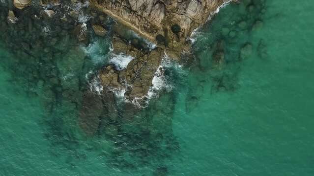 Aerial top view 4k footage by drone of ocean blue waves break on high cliff of a rocky mountain.Dream trip to green island. Outdoor adventure travel to beautiful phuket thiland beach.