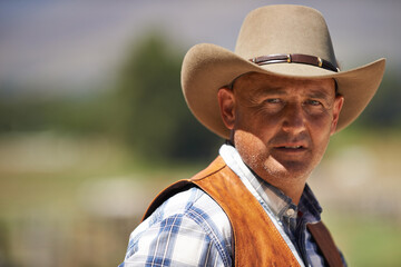 Portrait, confident cowboy and man at farm in the rural countryside for agriculture in Texas. Rancher, serious and face of male person in western hat outdoor in casual clothes in nature at stable - Powered by Adobe