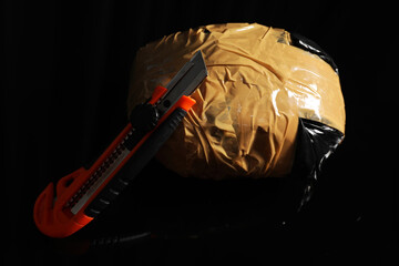 Smuggling, drug trafficking. Package with narcotics and utility knife on black surface