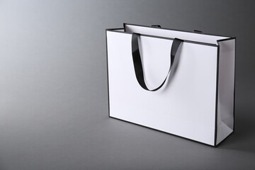 Naklejka premium One paper bag on grey background, space for text. Mockup for design