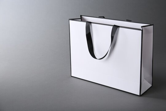 Fototapeta One paper bag on grey background, space for text. Mockup for design