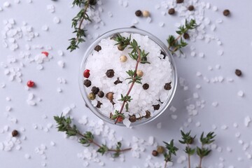Salt with peppercorns and thyme in bowl on light table, flat lay