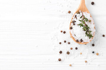 Salt with peppercorns, thyme and spoon on white wooden table, flat lay. Space for text