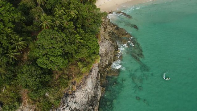 Aerial top view 4k footage by drone of ocean blue waves break on high cliff of a rocky mountain.Dream trip to green island. Outdoor adventure travel to beautiful phuket thiland beach.