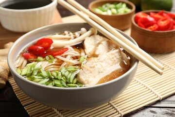 Delicious ramen with meat and ingredients on wooden table, closeup. Noodle soup