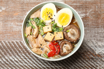 Bowl of delicious ramen on wooden table, top view. Noodle soup