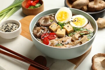 Bowl of delicious ramen and ingredients on white table. Noodle soup