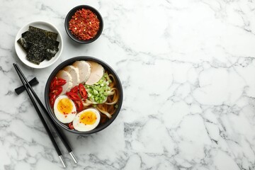 Delicious ramen in bowl served on white marble table, flat lay with space for text. Noodle soup