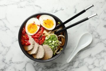 Delicious ramen in bowl and spoon on white marble table, flat lay. Noodle soup