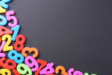 Colorful numbers on dark gray background, flat lay. Space for text