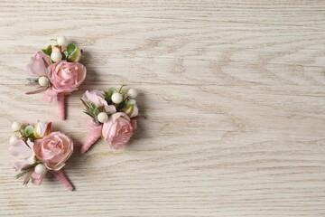 Stylish pink boutonnieres on white wooden table, flat lay. Space for text - obrazy, fototapety, plakaty