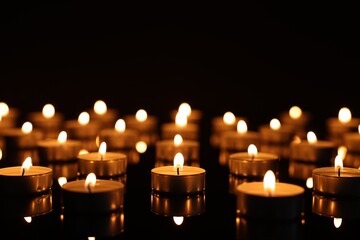 Burning candles on mirror surface in darkness