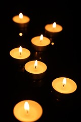Burning candles on mirror surface in darkness - obrazy, fototapety, plakaty