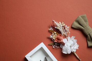 Wedding stuff. Stylish boutonniere, bow tie and cufflink on brown background, space for text