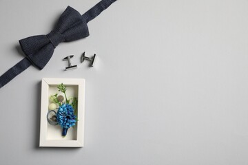 Wedding stuff. Stylish boutonniere, bow tie and cufflinks on gray background, flat lay. Space for...
