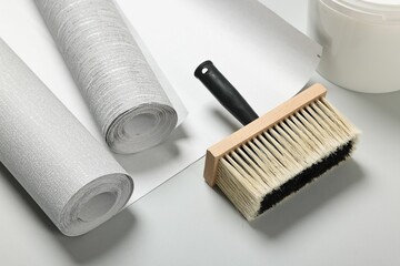 Different wallpaper rolls and brush on light grey background