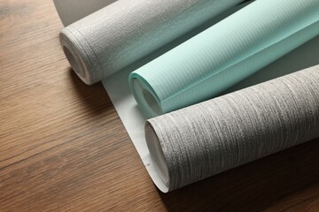 Different stylish wallpaper rolls on wooden table