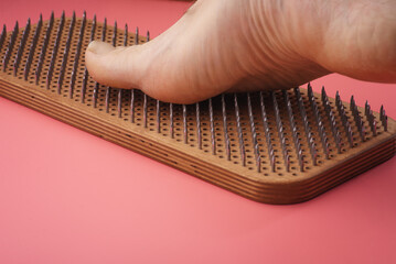 Woman's feet stand on a board with nails